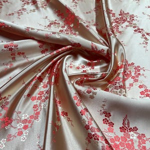 May include: Peach-coloured satin fabric with a repeating pattern of white and red cherry blossoms.