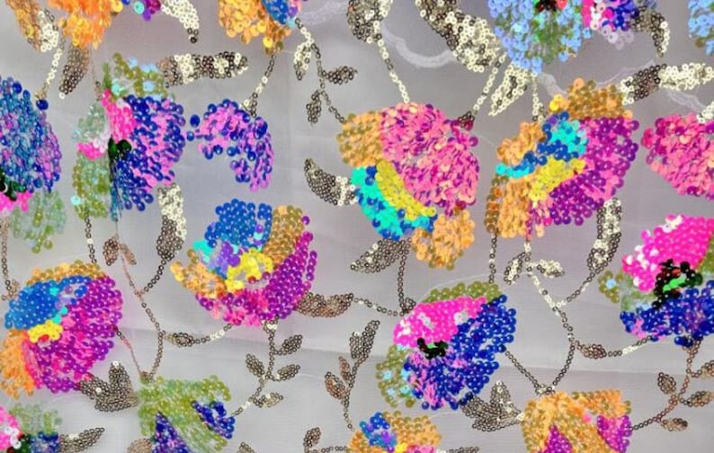 May include: A white sheer fabric with colourful sequins sewn in a floral pattern. The sequins are in shades of pink, blue, yellow, and green.