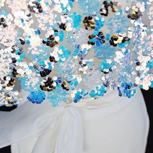 May include: White dress with a blue and silver sequined top. The top has a bow tie at the waist.