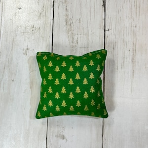May include: A green fabric pillow with a gold glitter Christmas tree pattern.