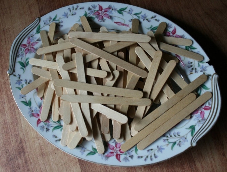 Puede incluir: Un plato ovalado de cer&aacute;mica blanca con un dise&ntilde;o floral presenta una pila de palitos de madera.