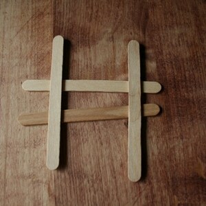Puede incluir: Cuatro palitos de madera dispuestos en forma de cruz para formar una estructura simple.
