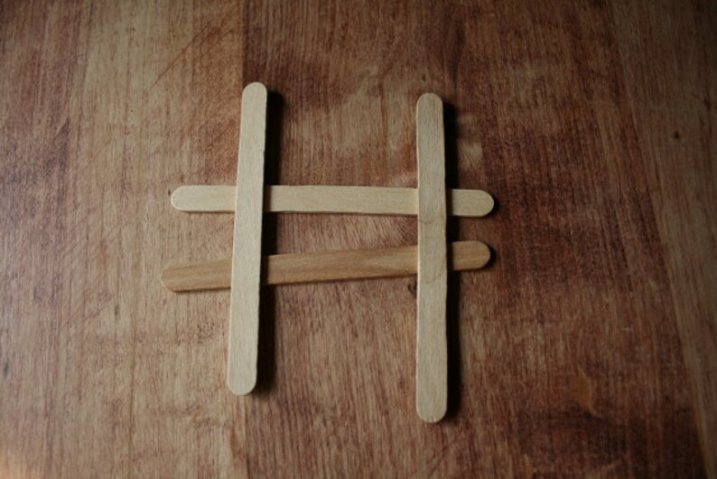 Puede incluir: Cuatro palitos de madera dispuestos en forma de cruz para formar una estructura simple.