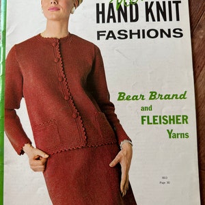 Puede incluir: Una portada de libro de patrones de tejido de punto vintage con una mujer que lleva un cárdigan y una falda de punto rojo. El texto de la portada dice "New Hand Knit Fashions Bear Brand and Fleisher Yarns" y "Vol. 90 - 85 cents".