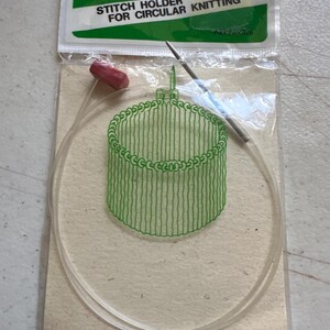 May include: A package of Clover brand stitch holder for circular knitting. The package includes a clear plastic needle with a red stopper, and a green illustration of a knitted cylinder. The package has the text "STITCH HOLDER FOR CIRCULAR KNITTING".