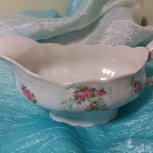 Sauce plat vintage en porcelaine, saucière, blanc avec motif floral rose, bleu et vert, poignée dorée et bord festonné