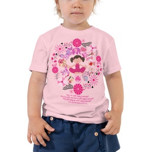 May include: Pink toddler t-shirt with a pink and white graphic of a girl meditating surrounded by flowers and animals. The text on the shirt reads: "May I be well, happy & peaceful. May my mom and dad be well, happy & peaceful. May all beings be well, happy & peaceful. #ourgorgeouslittlebuddha #peace"