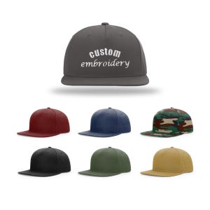 May include: A set of ten baseball caps in various colors, including black, navy blue, red, green, and camouflage. The caps are all the same style, with a flat brim and a curved crown. The front of each cap features the text "Custom Embroidery" in white.