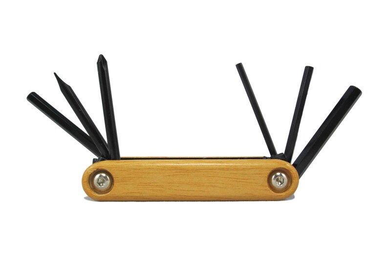 Peut inclure: Un outil multifonction en bois avec six cl&eacute;s Allen en m&eacute;tal noir. L'outil a une finition en bois naturel et est maintenu par deux vis argent&eacute;es.