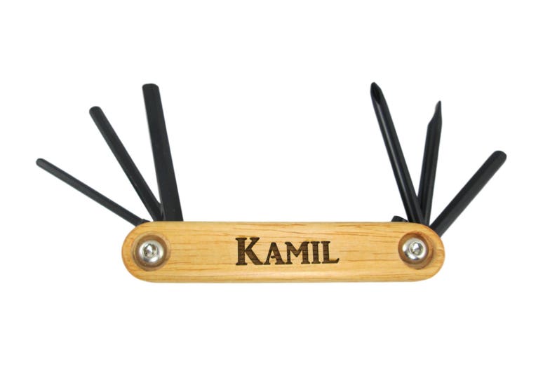 Peut inclure: Un outil multifonction en bois avec une poign&eacute;e en m&eacute;tal noir et six cl&eacute;s Allen de diff&eacute;rentes tailles. L'outil est grav&eacute; du nom "KAMIL".