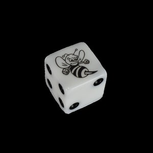 May include: White dice with black dots and a black and white bee illustration on one side.