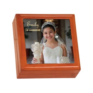 May include: A wooden box with a photo of a young girl in a white dress holding a candle. The text "Emily 1st communion" is printed on the box.