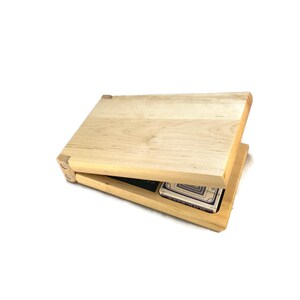 May include: A wooden box with a hinged lid, open to reveal a pack of cards inside. The box is made of light wood with a natural finish.