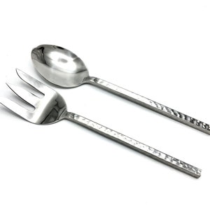 Puede incluir: Un juego de dos utensilios de servicio de plata con textura martillada. Los utensilios son un tenedor y una cuchara.