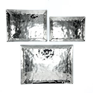 May include: Three silver hammered metal trays of different sizes. The trays are rectangular with slightly raised edges. The trays are arranged in a pyramid shape with the largest tray at the bottom and the smallest tray at the top.