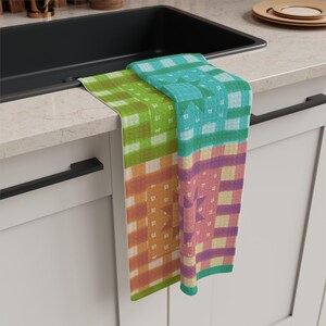May include: A rectangular kitchen towel featuring a patchwork design with various checkered and plaid patterns in shades of lime green, teal, orange, and purple. The fabric displays geometric star motifs integrated into the colourful grid layout.