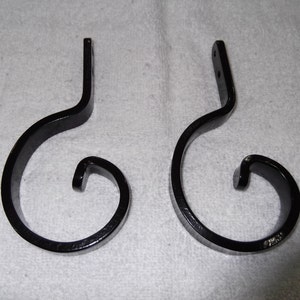 May include: Two black metal hooks with a curled design. The hooks are made of a sturdy metal and have a smooth, black finish.