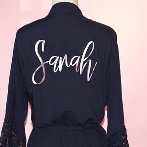 May include: Navy blue robe with lace trim on the sleeves. The robe has the name "Sarah" written on the back in silver lettering.