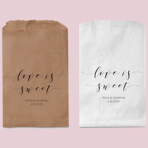 May include: Two paper bags with the text "love is sweet" printed on them. The bags are brown and white. The text also includes the names "Anna & Jonathan" and the date "2.12.2020".