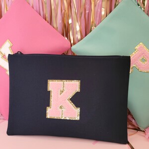 May include: Three zippered pouches with different letters on them. The pouches are pink, teal, and black. The letters are white, gold, and pink with gold glitter.