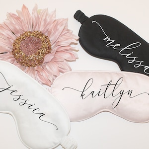 May include: Three satin sleep masks with personalized names: Jessica, Kaitlyn, and Melissa. The masks are white, pink, and black.