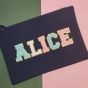 May include: A black canvas zippered pouch with the name "Alice" in colorful, glittery letters.