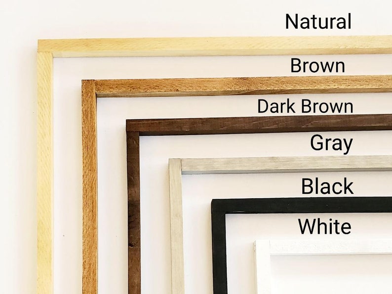 May include: A set of six picture frames in various colors, including natural, brown, dark brown, gray, black, and white. The frames are arranged in a vertical stack, with the natural frame at the top and the white frame at the bottom.