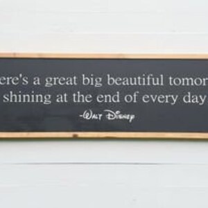 Puede incluir: Un letrero de pared rectangular con fondo negro y marco de madera natural. El texto en blanco dice: There's a great big beautiful tomorrow shining at the end of every day. -Walt Disney. El letrero est&aacute; orientado horizontalmente.