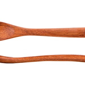 Puede incluir: Una cuchara de madera con un cuenco redondeado y un mango largo y delgado. La cuchara est&aacute; hecha de madera marr&oacute;n claro y tiene un acabado liso y pulido.