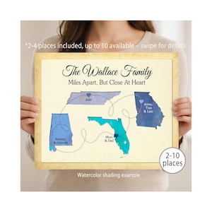 May include: A framed watercolor map print with the text "The Wallace Family Miles Apart, But Close At Heart." The map features blue states connected by dotted lines, with names and locations. The frame is a light wood color.