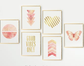 May include: A collection of six framed wall art prints featuring gold frames and white backgrounds. The prints display a pink watercolour circle, stacked triangles, a gold striped heart, the text GOOD VIBES ONLY, a chevron pattern, and a butterfly.