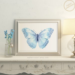 Op de afbeelding: Een ingelijste aquarelprint van een lichtblauwe vlinder met complexe vleugelpatronen. Het kunstwerk zit in een lichtgekleurde lijst. De tekst 'Digital Download' staat rechtsboven en 'ephericaart.etsy.com' staat onder de lijst gedrukt.