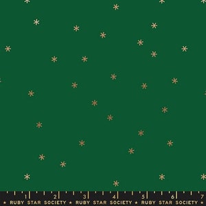 May include: A green fabric with a repeating pattern of gold snowflakes. The fabric is marked with a ruler in inches and the text "RUBY STAR SOCIETY".