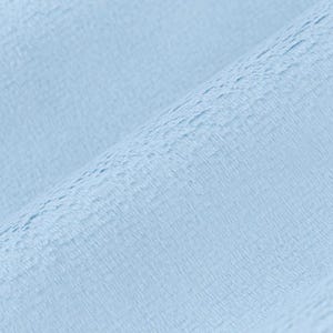 May include: Close-up of a light blue, textured fabric. The fabric has a soft, plush appearance with a subtle, rippled pattern. The color is a pale, calming blue, suggesting a cozy textile.