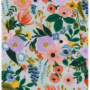 May include: Fabric sample with a floral design. The pattern features a variety of flowers in pink, purple, orange, and blue, set against a pale green backdrop. The design includes roses, tulips, and other blooms, with green leaves and stems.