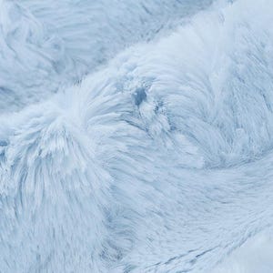 May include: Close-up of a soft, light blue faux fur fabric. The fabric has a fluffy, plush texture.