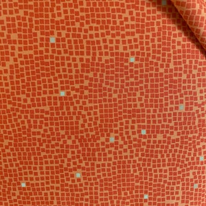 May include: A close-up of a fabric with a repeating pattern of small orange squares with a subtle white dot pattern.