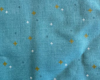 May include: A teal blue fabric with a repeating pattern of small white and gold crosses.