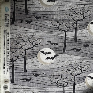 May include: Black and white fabric with a Halloween theme. The design features a night landscape with trees, bats, crows, and full moons. The fabric is 100% certified organic cotton.