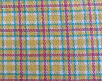 May include: A yellow, red, and blue plaid fabric with a woven texture.