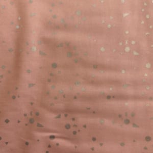 May include: A pink fabric with a silver geometric pattern. The pattern includes circles, triangles, and squares.