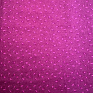 May include: A close-up of a fabric with a repeating pattern of small, bright pink lightning bolts scattered across a deep magenta background. The fabric has a slightly textured appearance.