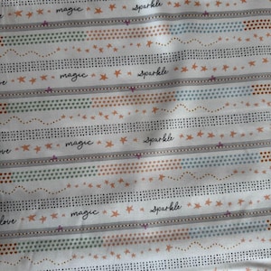 May include: White fabric with a repeating pattern of horizontal stripes. The stripes feature dotted lines, stars, and hearts in various colors, including orange, green, and blue. The words "magic" and "sparkle" are written in cursive.