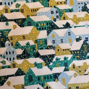 May include: A fabric pattern featuring a village scene with houses in shades of green, yellow, and blue, covered in snow. The houses have white roofs and are decorated with small windows. The overall design has a whimsical, wintery feel.