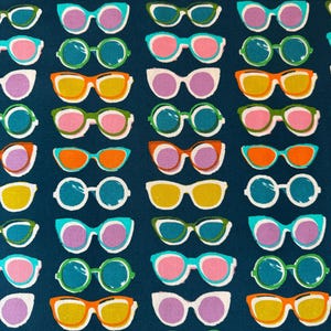 May include: A dark blue fabric featuring a repeating pattern of sunglasses in various colors including orange, yellow, green, teal, and purple. The sunglasses are arranged in rows and columns, showcasing different frame shapes and lens color combinations.
