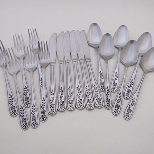 May include: A set of stainless steel cutlery comprising forks, knives and spoons. Each item has a polished silver finish and a decorative embossed floral pattern along the handle, featuring a single rose bloom and leafy vine stems.