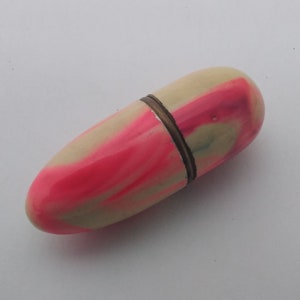May include: A small, egg-shaped, pink and white marbled container with a metal band around the middle.