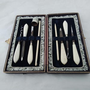 Cased antique manicure vanity set with thimble, perfume bottle corkscrew, button hook, etc