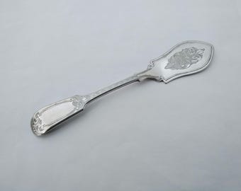 May include: A silver butter knife with an ornate handle and a decorative design on the blade.