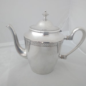 May include: A silver teapot with a decorative design around the body and a lid with a knob on top.